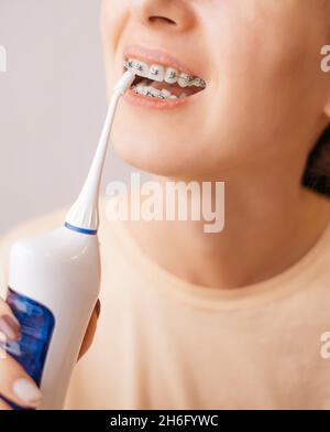 Donna lavaggio di un bretelle con un irrigatore per la salute dentale. Foto Stock