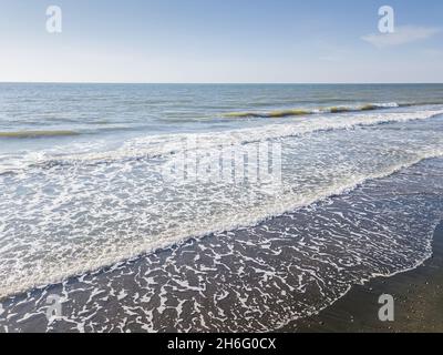 Vista con droni della spiaggia di sabbia del mare con grandi onde in una giornata di sole Foto Stock