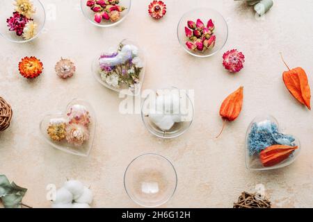 Ornamenti fai-da-te riempiti di fiori secchi su fondo di cemento beige. Albero di Natale decorazione idea. Vista dall'alto, piatto Foto Stock