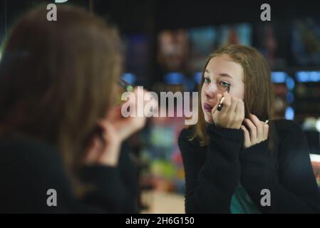 Ragazza adolescente che prova i prodotti cosmetici nel negozio di cosmetici. Fare il make-up. Foto Stock