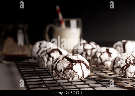 Deliziosi biscotti al cioccolato fatti in casa con grata glassa di zucchero a velo per il raffreddamento su sfondo tavolo di pietra scura. Foto Stock