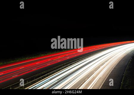 Percorsi leggeri da un'autostrada o autostrada trafficata di notte che mostrano il movimento del traffico all'ora di punta. Ampia area vuota con spazio di copia per il testo Foto Stock