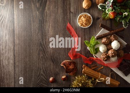 Sfondo del tavolo di Natale con palle di cioccolato e cocco su tavola di legno con ingredienti e noci. Vista dall'alto. Foto Stock