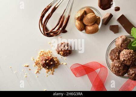 Preparazione di palle di cioccolato con scaglie di mandorle su un banco bianco con utensili da cucina. Vista dall'alto. Composizione orizzontale. Foto Stock