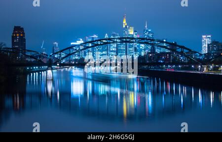 15 novembre 2021, Hessen, Francoforte sul meno: Le luci dello skyline bancario di Francoforte brillano di notte mentre una nave che passa lascia un sentiero di luce sul fiume meno. Nel frattempo, le incidenze della corona continuano ad aumentare a livello nazionale. Foto: Boris Roessler/dpa Foto Stock