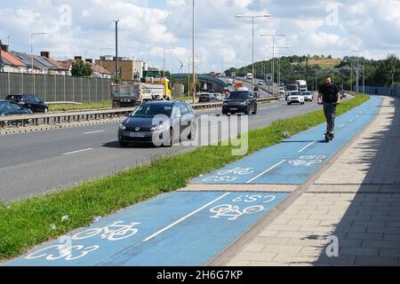 Uomo su e-scooter sulla Cycle SuperHighway 3, Cycleway 3, sulla A13 Newham Way Road, Londra, Inghilterra, Regno Unito, Regno Unito Foto Stock