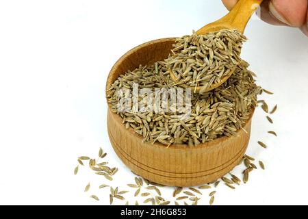 Chef che prende semi di cumino secco tritati o spezie zira da vaso di spezie in legno. Messa a fuoco selettiva. Concentratevi sulle spezie nel vaso. Primo piano. Foto Stock