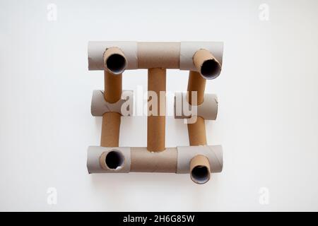 Struttura astratta progettata con tubi di carta di cartone beige isolati su sfondo bianco da un'angolazione elevata Foto Stock