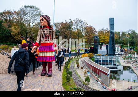 Little Amal è visto camminare vicino a uno degli edifici in miniatura del parco.amare, un nuovo centro culturale nel centro dell'Aia ha organizzato come parte del suo 'Open Festival', la visita del gigante pupazzo 'Little Amal', Una bambina di rifugiati siriani di nove anni e alta oltre 11 metri fino al parco in miniatura, Madurodam. È invitata a partecipare al Festival come ospite speciale della città per attirare l'attenzione in tutta Europa sulla situazione dei giovani rifugiati fuggiti dalla Siria. Amal è stata ricevuta fuori dal parco da un gruppo di bambini, dopo di che poteva camminare intorno alle repliche modello in scala 1:25 Foto Stock