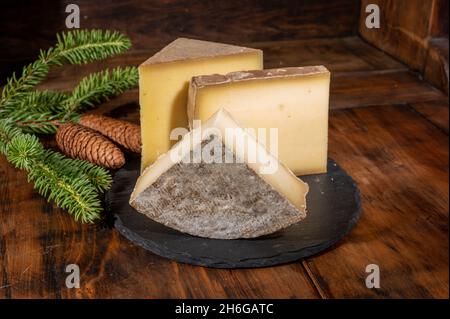 Collezione di formaggi, formaggi francesi di mucca comte, beaufort, abondance, tomo de savoie e coni di abete Foto Stock