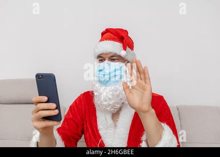 Vestito come Babbo Natale che parla tramite videoconferenza Foto Stock