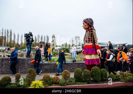 I bambini sono visti dopo Little Amal durante il festival.amare, un nuovo centro culturale nel centro dell'Aia ha organizzato come parte del suo 'Open Festival', la visita del gigante burattino 'Little Amal', una bambina siriana di nove anni e oltre 11 piedi di altezza al parco in miniatura, Madurodam. È invitata a partecipare al Festival come ospite speciale della città per attirare l'attenzione in tutta Europa sulla situazione dei giovani rifugiati fuggiti dalla Siria. Amal è stata ricevuta fuori dal parco da un gruppo di bambini, dopo di che poteva camminare intorno alle repliche in scala 1:25 del famoso olandese Foto Stock