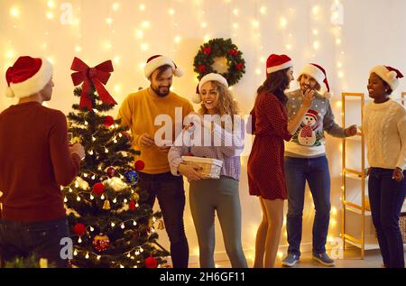 Giovani felici che si divertono e decorano albero di Natale a festa con gli amici Foto Stock