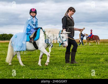 Spettacolo estivo di cavalli: Un bambino su un pony vestito come unicorno in un concorso di abbigliamento di fantasia, East Lothian, Scozia, Regno Unito Foto Stock