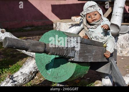 Verkhnotoretske, Donetsk, Ucraina. 16 ottobre 2021. Una bambola di legno con una mitragliatrice fatta per divertimento è visto all'entrata del piccolo negozio alla periferia del villaggio di Verkhnotoretske.Verkhnotoretske è un insediamento urbano ucraino-tipo situato sulla prima linea nel distretto di Yasynuvata in Donetsk oblast dell'Ucraina orientale. Durante la guerra di Donbas, iniziata a metà aprile 2014, la linea di separazione tra le parti in guerra è stata situata nelle vicinanze dell'insediamento. Il villaggio era una zona grigia fino alla fine del 2017. Oggi Verkhnotoretske è un territorio ucraino. Il conflitto Foto Stock