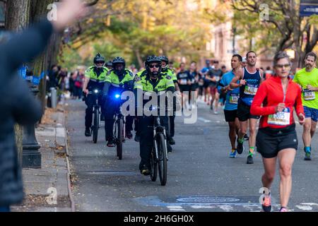 Una falanga di ufficiali NYPD in bicicletta a Harlem a New York vicino al 22 miglia marchio vicino a Mount Morris Park la Domenica, 7 novembre 2019 nella 50 ° corsa della maratona TCS New York City. Circa 30,000 corridori. Giù dal solito 50,000, hanno partecipato alla gara che è stata cancellata l'anno scorso a causa della pandemia. (© Richard B. Levine) Foto Stock