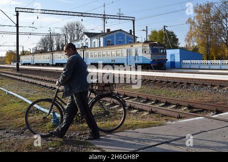 Verkhnotoretske, Donetsk, Ucraina. 16 ottobre 2021. Un uomo con una bicicletta è visto attraversare una ferrovia sulla stazione ferroviaria nel villaggio di Verkhnotoretske.Verkhnotoretske è un insediamento ucraino di tipo urbano situato sulla prima linea nel distretto di Yasynuvata in Donetsk oblast dell'Ucraina orientale. Durante la guerra di Donbas, iniziata a metà aprile 2014, la linea di separazione tra le parti in guerra è stata situata nelle vicinanze dell'insediamento. Il villaggio era una zona grigia fino alla fine del 2017. Oggi Verkhnotoretske è un territorio ucraino. Il conflitto ha portato avanti entrambe le civili Foto Stock