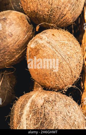 Noci di cocco mature al mercato degli agricoltori. Vendita di prodotti esotici ecologici biologici. Frutta tropicale in un cestino. Foto Stock