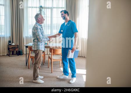 Paziente contento che saluta il medico a casa sua Foto Stock