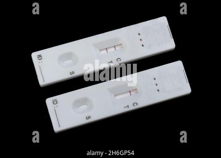 Due test di flusso laterale rapido Covid-19, uno che mostra un risultato negativo l'altro positivo (test antigene) Foto Stock