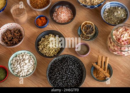 Ciotola piena di ingredienti, fagioli neri, fagioli bianchi, bastone di cannella, cardamomo puzzolente, Sale himalayano, pasta, anice stellato, paprika e altre cose Foto Stock