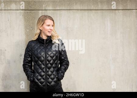 Ritratto sorridente di bella donna bionda in giacca trapuntata Foto Stock