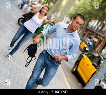 Bandit uomo che corre con la borsa dopo rubato questo da emotivo femmina Foto Stock