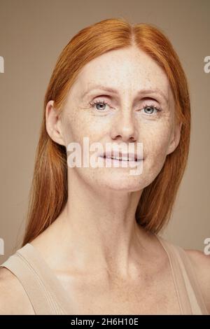 Ritratto verticale minimo di giovane donna dai capelli rossi con volcini che guardano la fotocamera Foto Stock