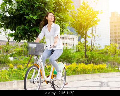 Giovane donna attraente in bicicletta nel parco della città Foto Stock