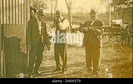 Un gruppo di uomini sconosciuti posano con fucili durante un fine settimana di caccia nel Queensland rurale, probabilmente negli anni trenta. Dalla collezione della famiglia McKechnie. Foto Stock