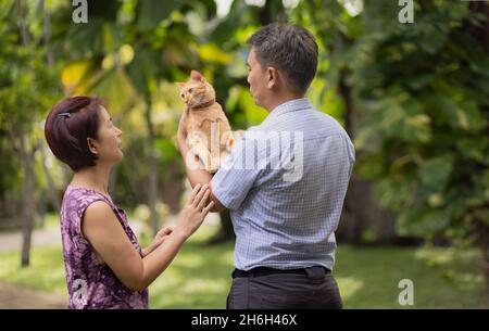 Coppia di mezza età rilassante con gatto in cortile. Foto Stock