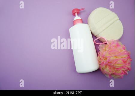 Prodotti da bagno a fondo piatto doccia bottiglia con soffio doccia e spazzola per capelli su sfondo viola Foto Stock