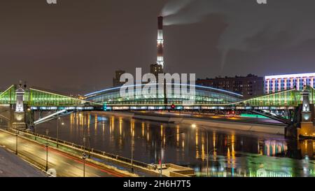 Vista del colorato ponte Bogdan Khmelnitsky illuminato di notte che si riflette nel fiume Moskova. Ponte pedonale sul fiume Moskva. Mosca Foto Stock