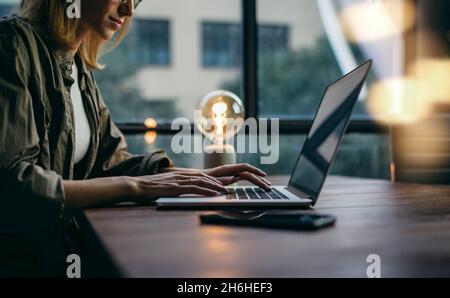 Giovane donna che lavora con un notebook. Freelance femminile che si connette a internet via computer. Blogger o giornalista che scrive nuovo articolo. Foto Stock