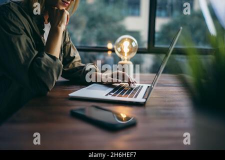 Giovane donna che lavora con un notebook. Freelance femminile che si connette a internet via computer. Blogger o giornalista che scrive nuovo articolo. Foto Stock