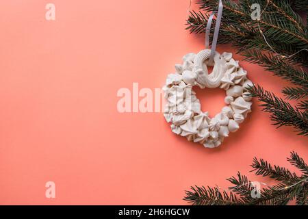 Meringa di Natale sul ramo di abete sullo sfondo di colore corallo vivente. Concetto di scheda. Vista dall'alto. Disposizione piatta Foto Stock