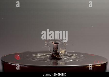 Spruzzi d'acqua su una superficie che produce sculture d'acqua su uno sfondo grigio con spazio di copia Foto Stock