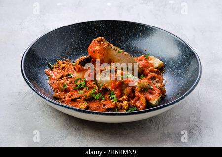 Zander arrosto servito con pomodoro al vapore, cipolla e salsa di olive su un piatto Foto Stock