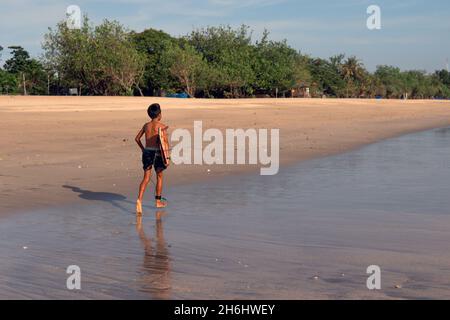 surfista in pantaloncini neri camminando lungo la spiaggia. bali Foto Stock