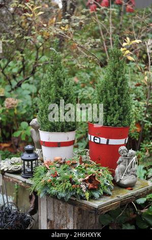 Decorazioni natalizie in giardino. Corona di Natale fatta di falso cipresso e abete su un tavolo di legno Foto Stock