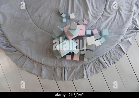 Cubi giocattolo multicolore in colori pastello sul tappeto nella camera dei bambini, vista dall'alto Foto Stock