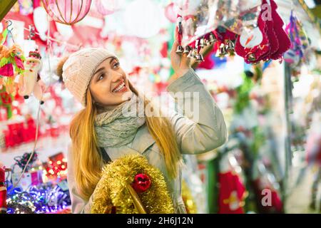 Bella ragazza sorridente che sceglie decorazione di Natale Foto Stock