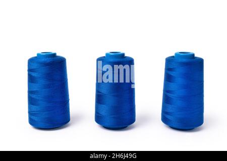 Fili di blu elettrico trendy su uno sfondo bianco. Vista laterale di tre bobine di filo da cucire. Foto Stock