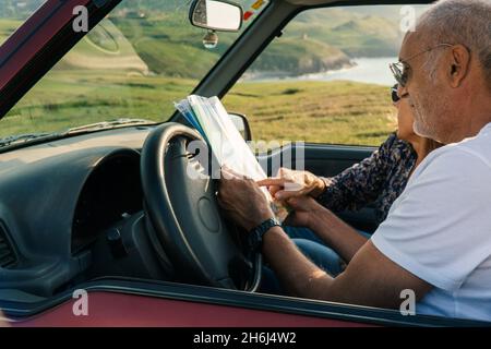 Coppia anziana che guarda una mappa attraverso la costa nella loro 4x4 cabriolet auto Foto Stock