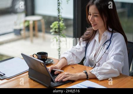 Ritratto felice medico donna asiatica, Telemedicina concetto. Medico asiatico che parla con il paziente utilizzando notebook video online webinar consultazione mentre Foto Stock