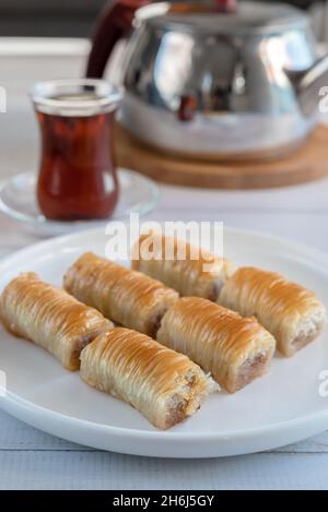 Ancora vita in stile turco: Un piatto con baklava, un bicchiere di tè e un teiera. Scatto verticale. Foto Stock