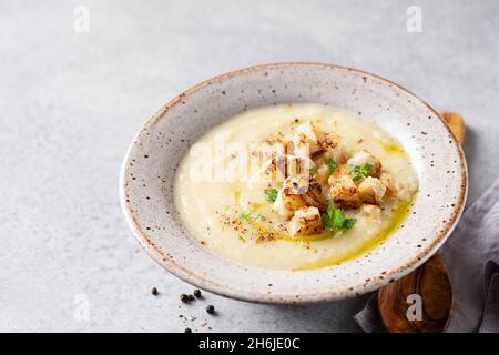 Zuppa di crema di cavolfiore in ciotola servita con olio d'oliva e crostini di pane. Spazio di copia Foto Stock