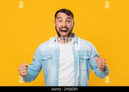 Felice emozionale eccitato medio invecchiato attraente maschio caucasico urlando, gioisce per vincere Foto Stock