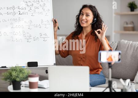 Insegnante femminile che mostra il gesto giusto, spiegando la matematica agli studenti Foto Stock