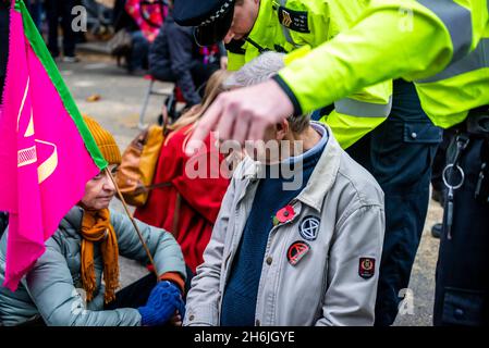 Polizia che si impegna con un protestore che rifiuta di muoversi dalla strada, Rise and Rebel march, Extinction Rebellion, Londra, Regno Unito. 13 novembre 2021 Foto Stock